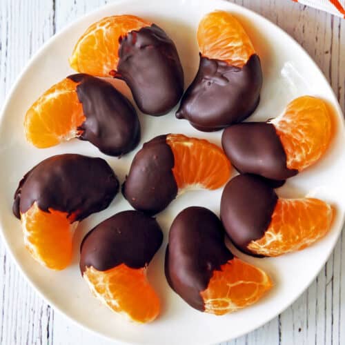 Chocolate-covered oranges served on a white plate.
