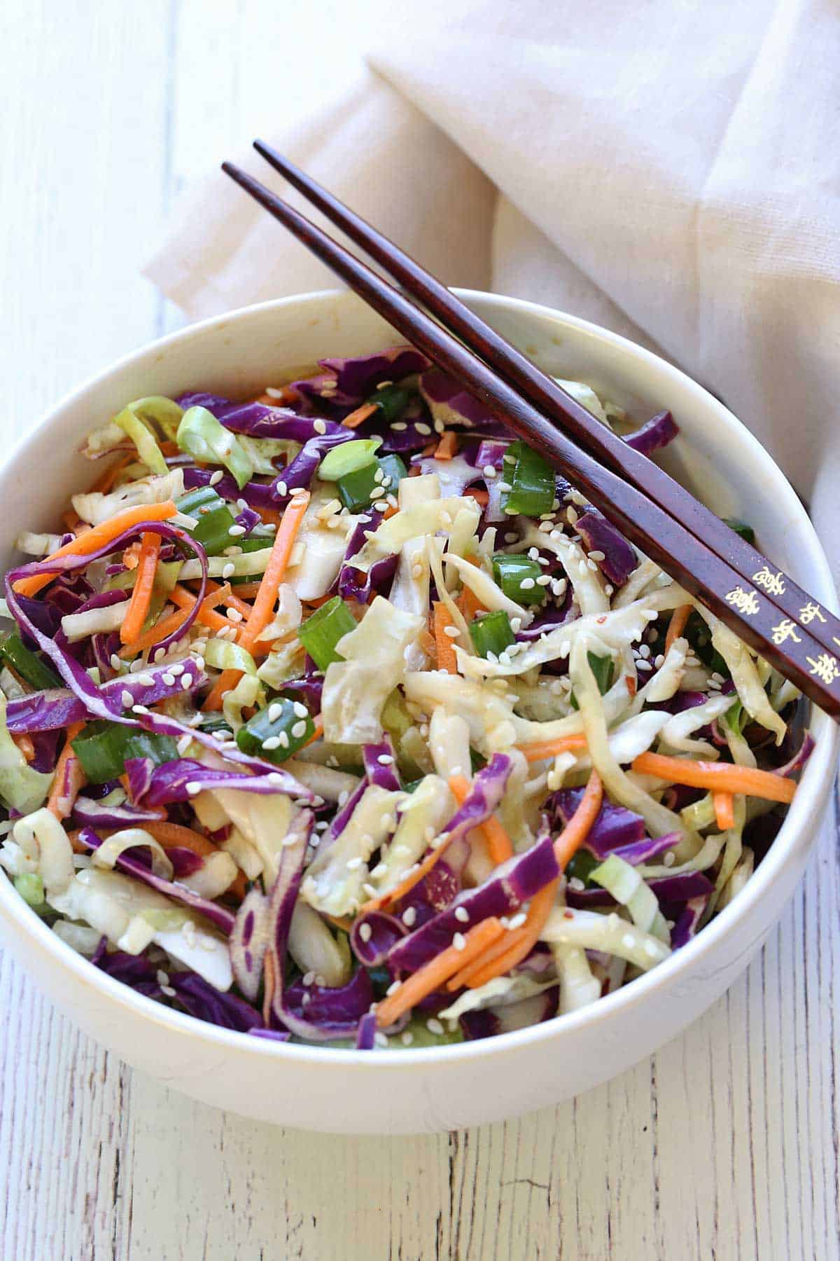 Asian cabbage salad served in a white bowl with chopsticks. 