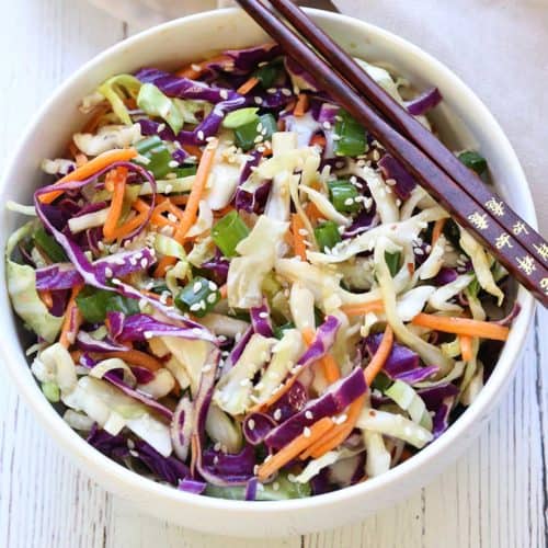 Asian cabbage salad served in a white bowl with chopsticks.