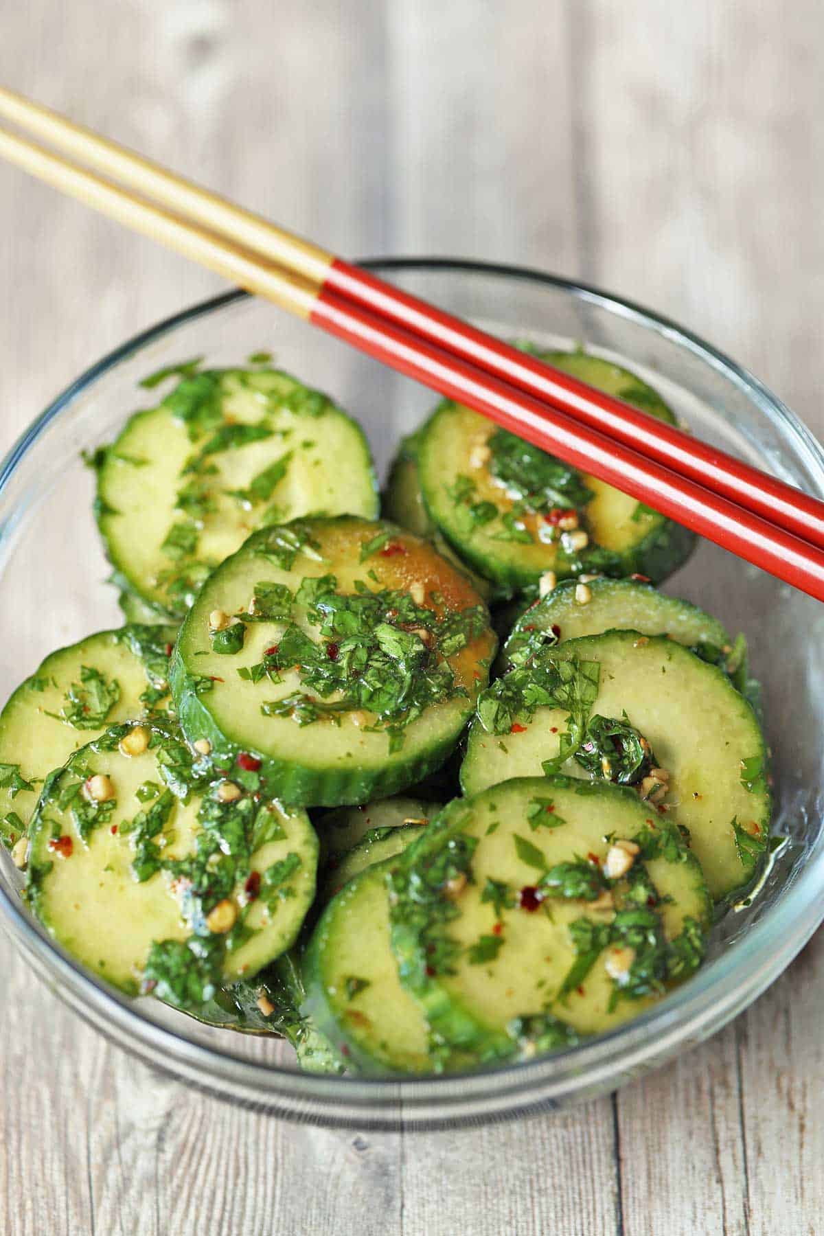 Asian cucumber salad served with red chopsticks.