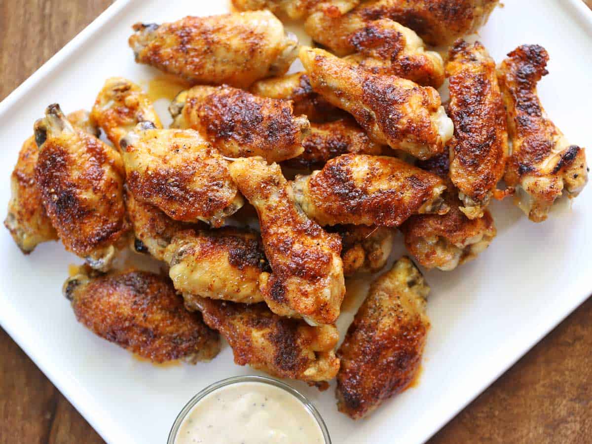 Baked chicken wings are served on a white plate.