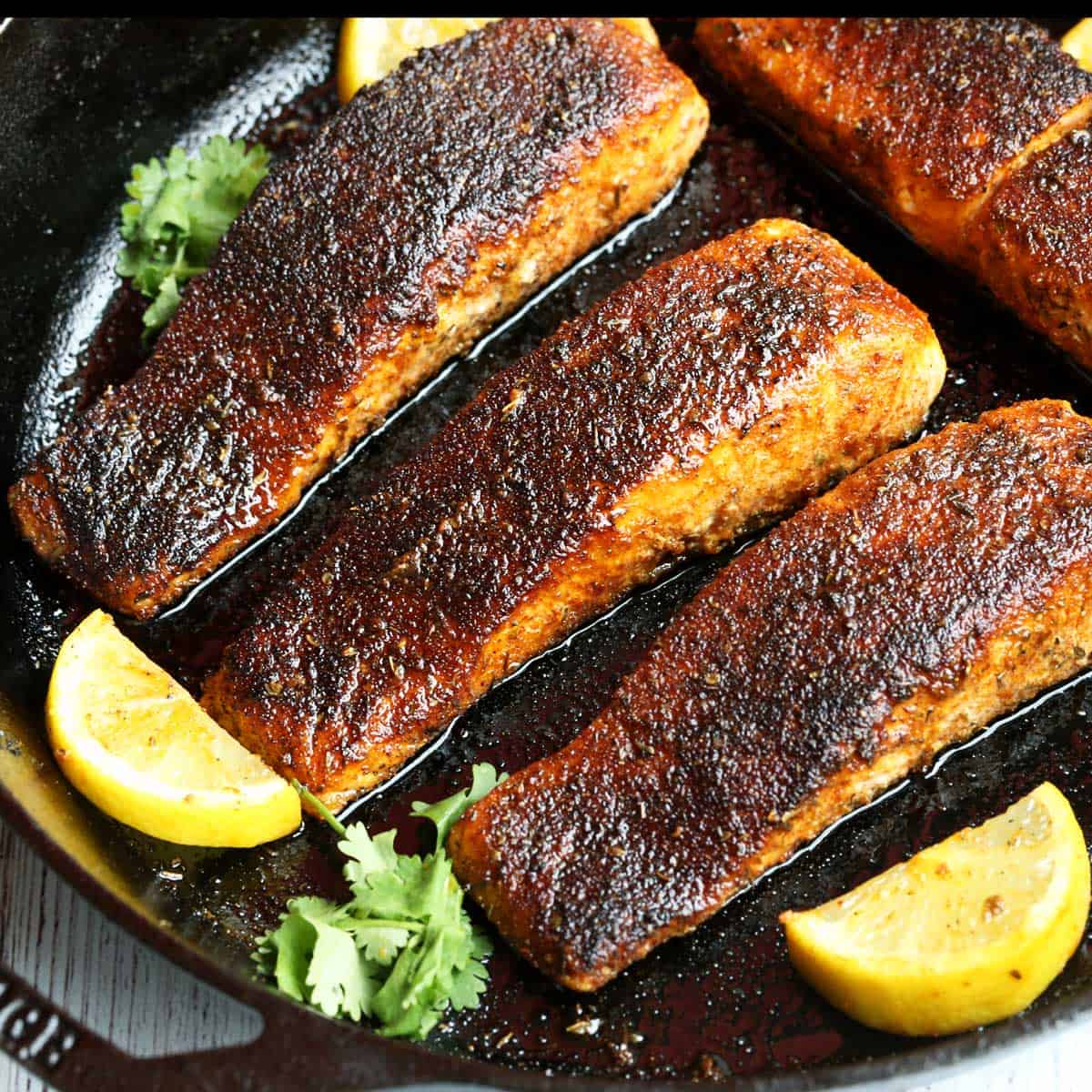 Blackened salmon served with lemon slices.