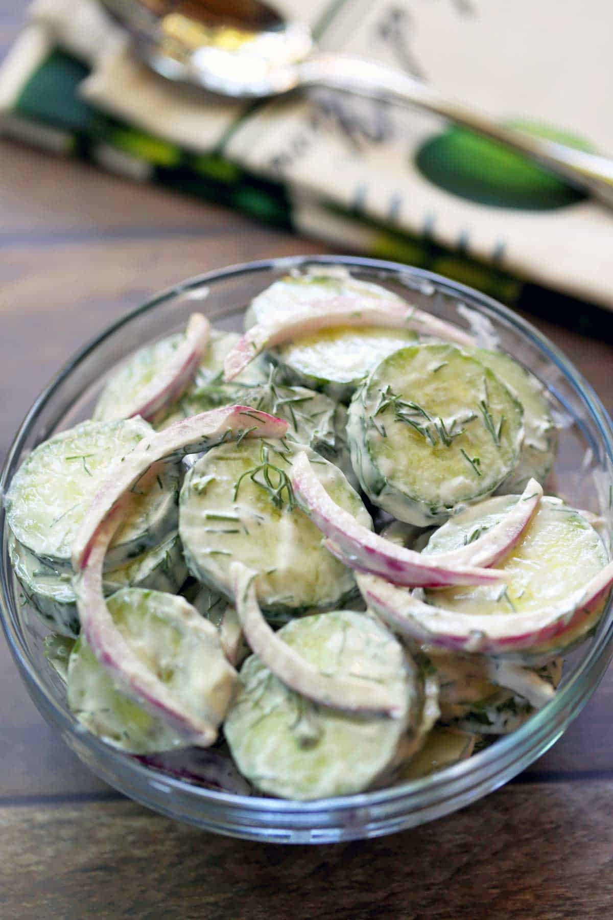 Creamy cucumber salad with onions, dill and sour cream, served in a glass bowl.