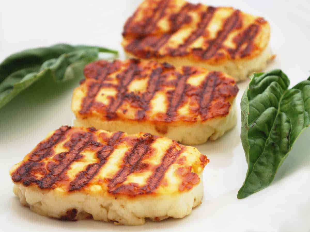 Slices of grilled halloumi cheese on a white plate.