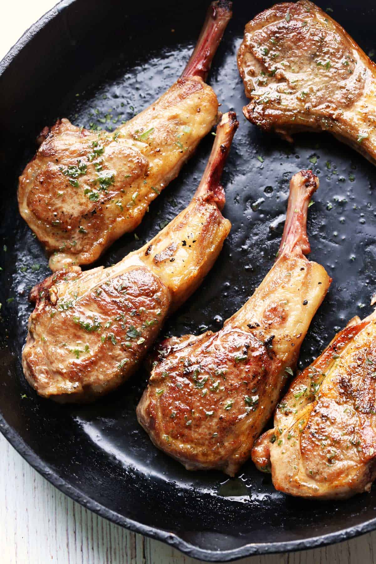 Pan fried lamb chops in a cast-iron skillet.