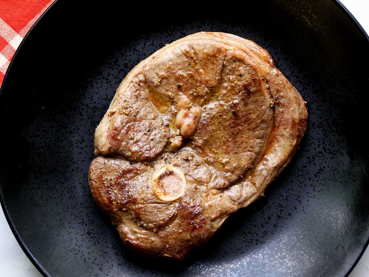 lamb steak served on a dark plate.