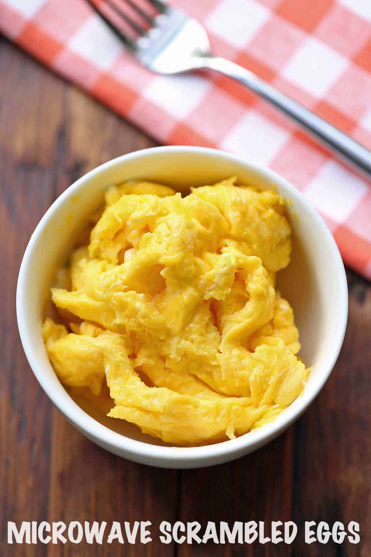 Microwave scrambled eggs served with a bowl with a napkin and a fork.