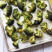 Oven-roasted broccoli on a parchment-lined baking sheet.