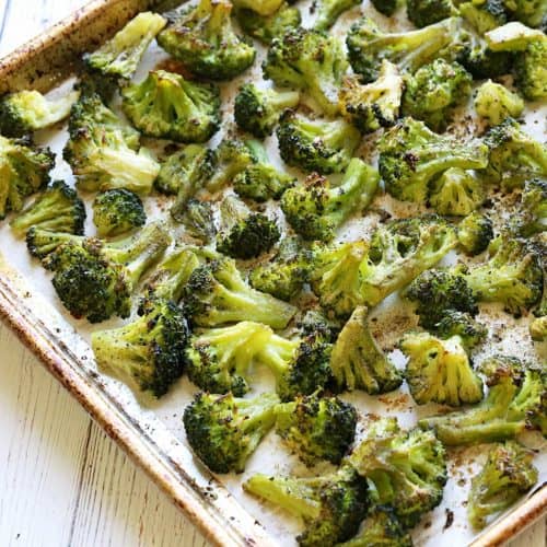 Roasted frozen broccoli on a parchment-lined baking sheet.