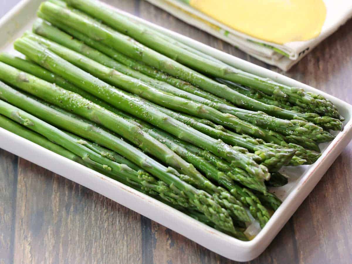 Steamed asparagus on a white serving tray.