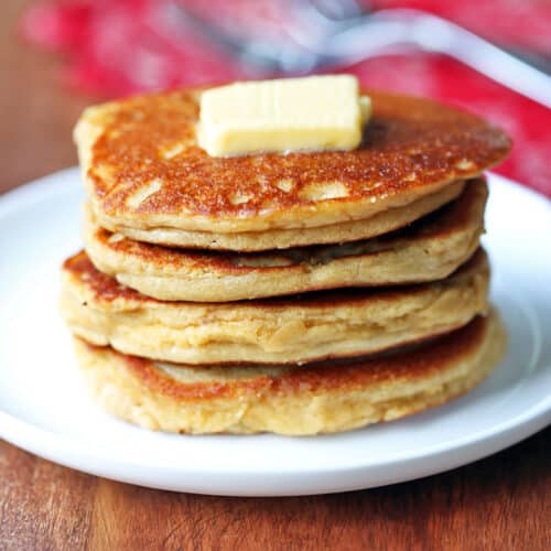 Almond flour pancakes stacked on a plate and topped with butter.