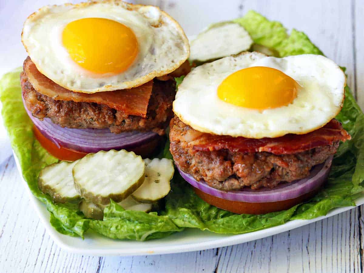 Two bacon burgers topped with fried eggs.