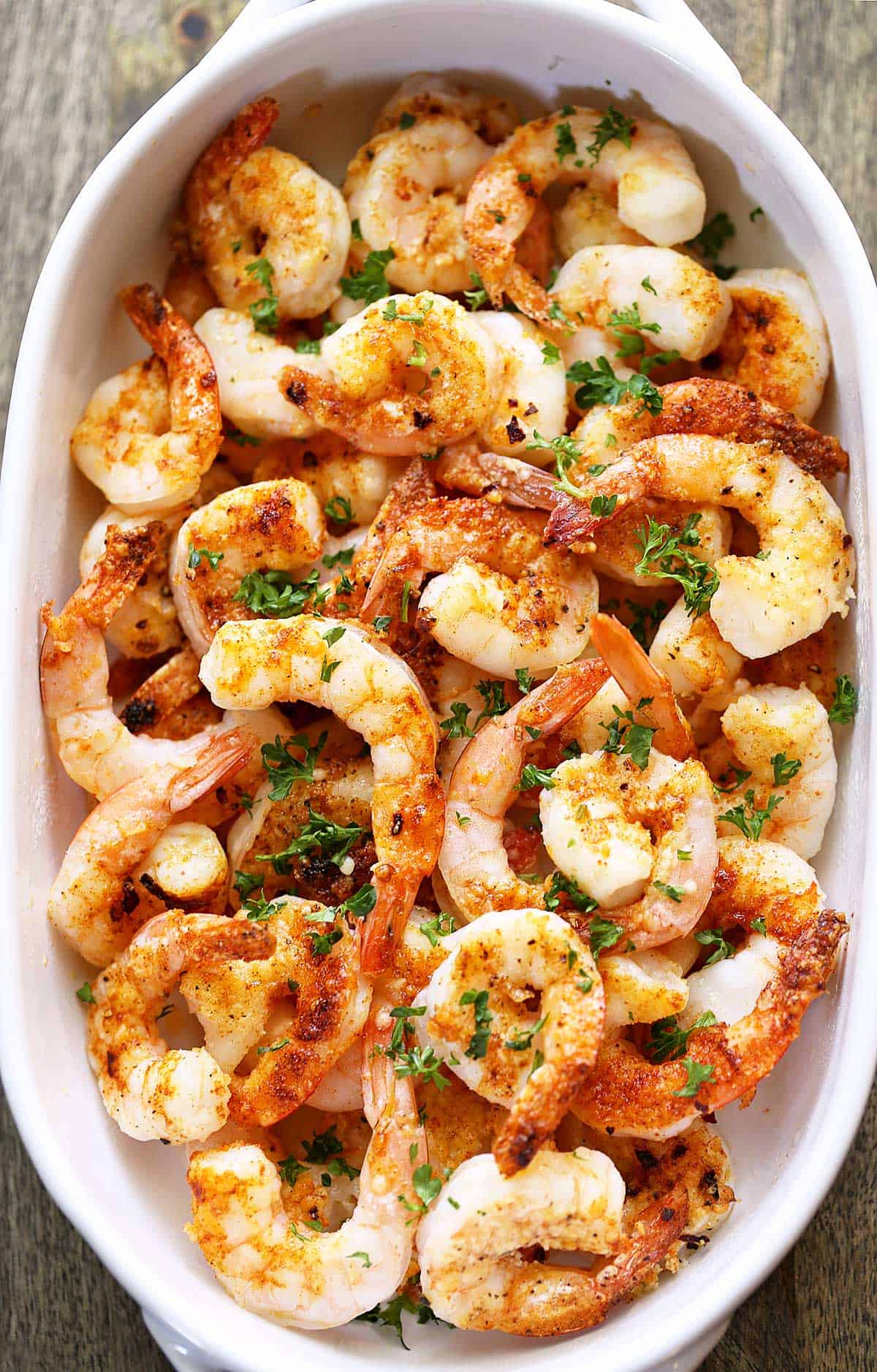 Baked shrimp are served in a white baking dish. 