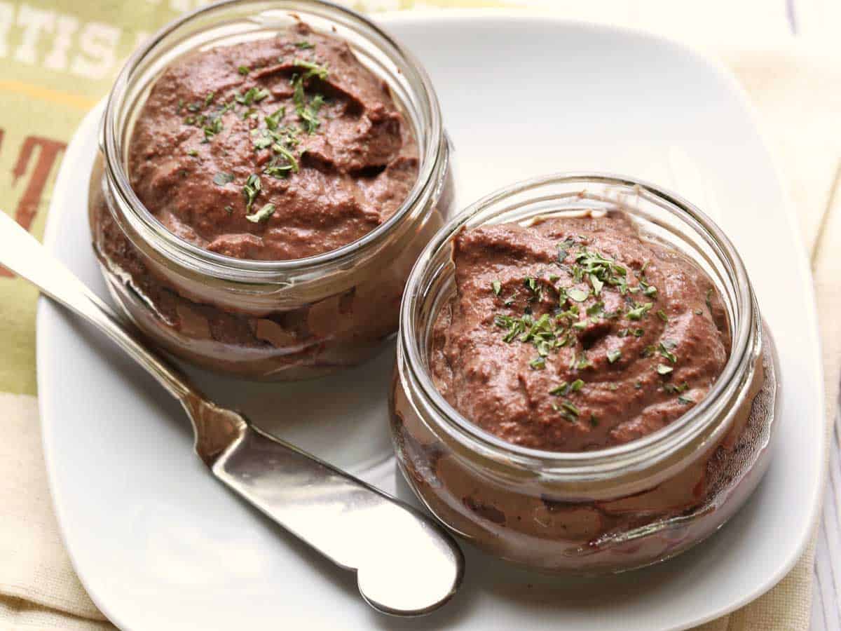 Chicken liver pate served in small jars and topped with parsley. 