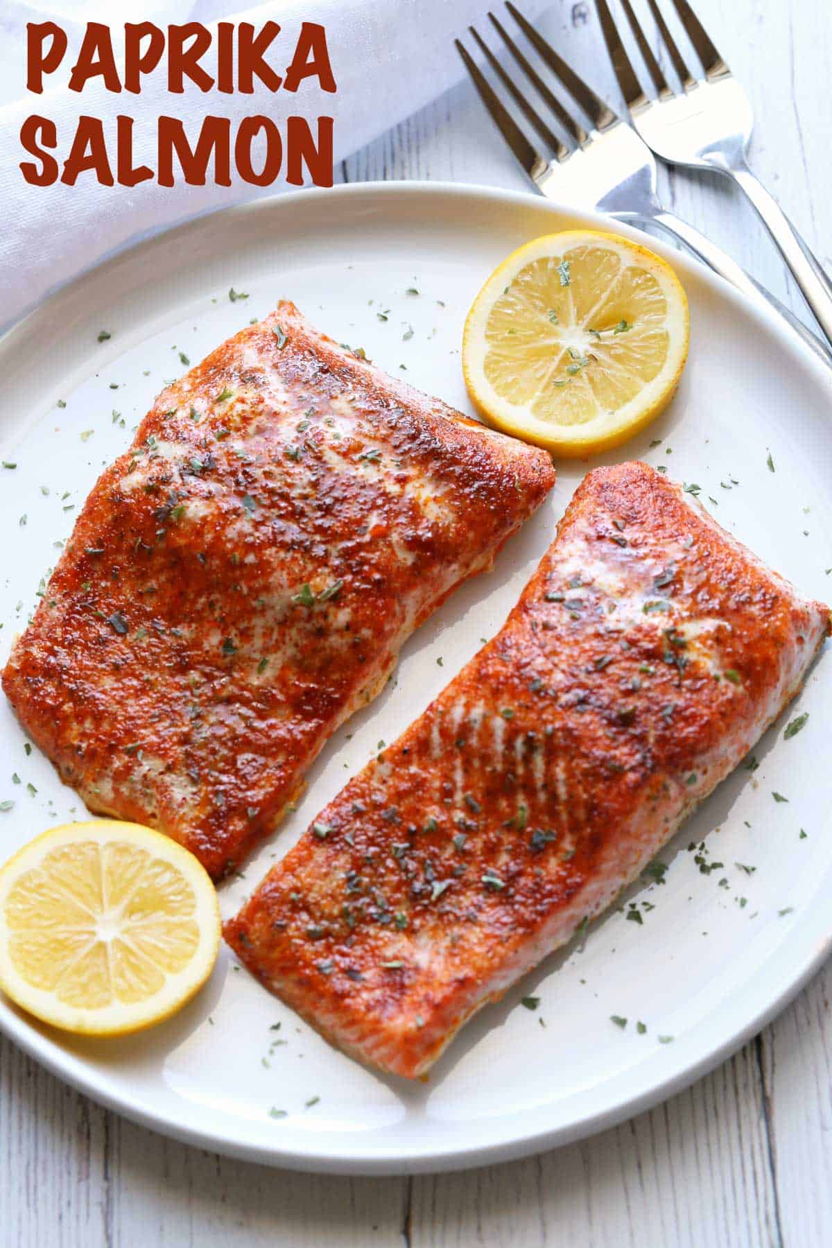 Salmon seasoned with paprika, served on a plate with lemon slices
