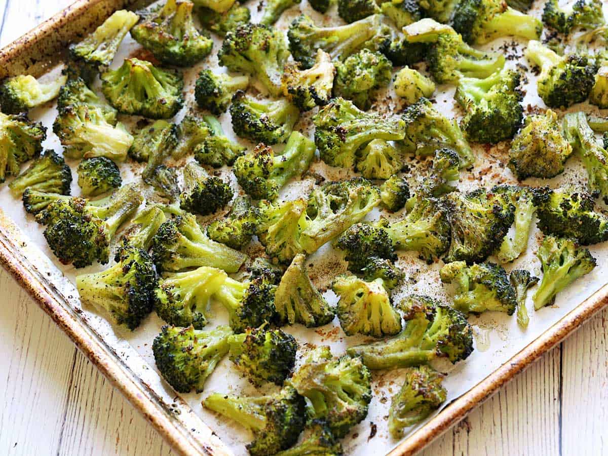 Roasted frozen broccoli florets on a large baking sheet. 