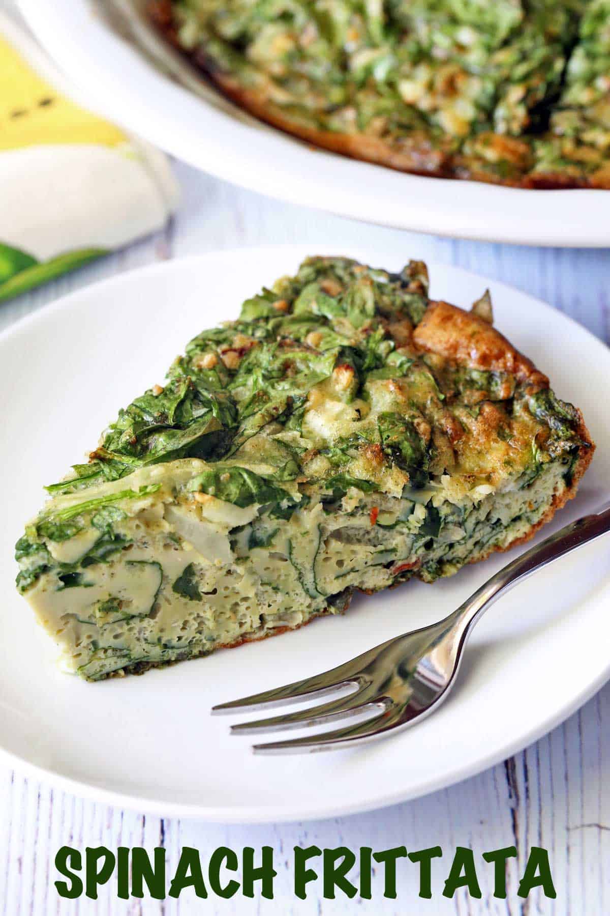 A slice of spinach frittata served on a plate with a fork.