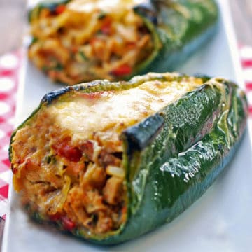 Stuffed poblano peppers served on a white plate with a napkin.