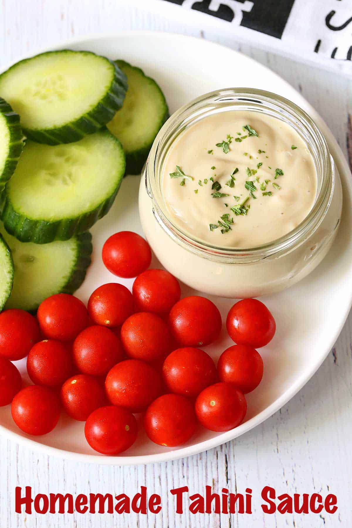 Tahini sauce served with cucumber slices and tomatoes. 