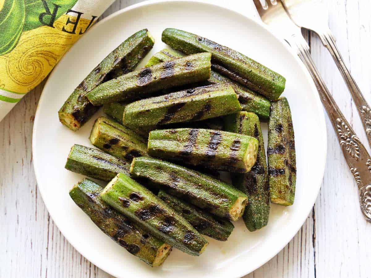 Grilled okra served on a white plate with forks.