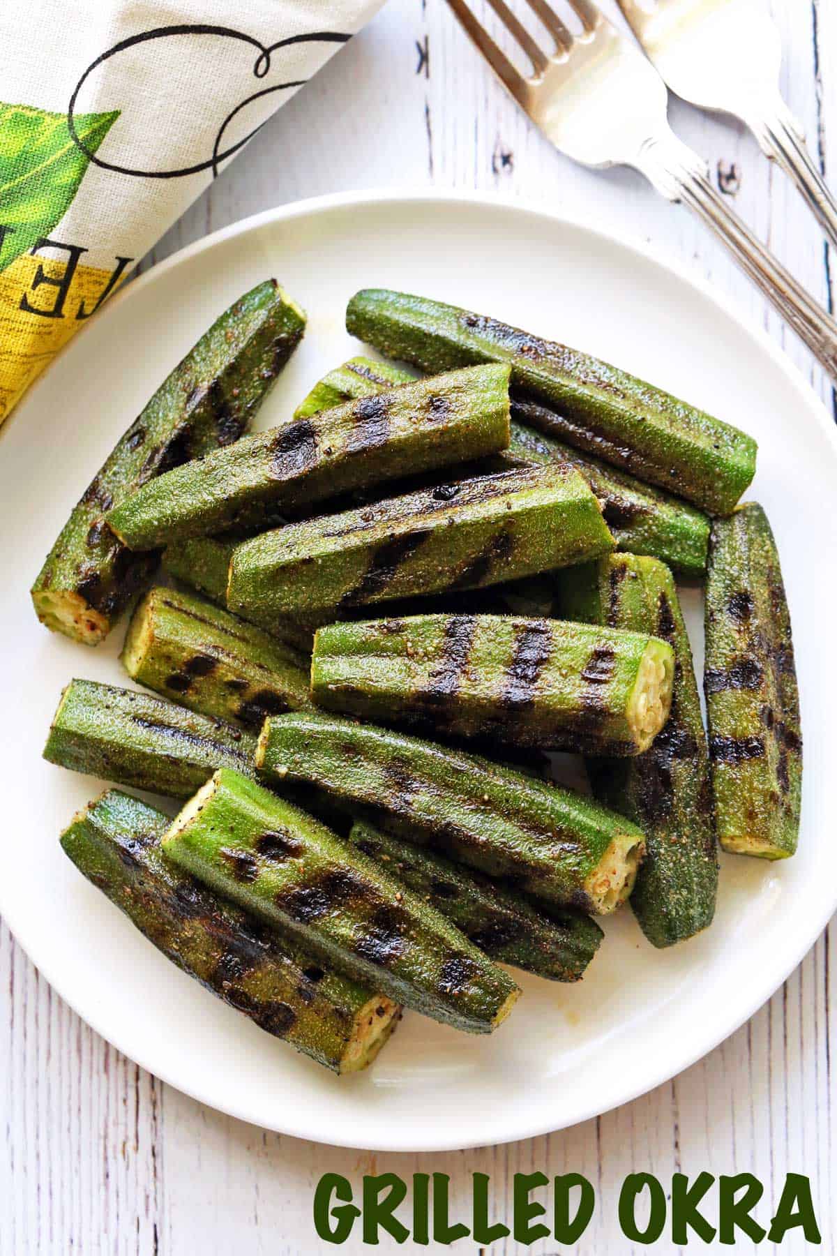 Grilled okra served on a plate with utensils and a napkin. 
