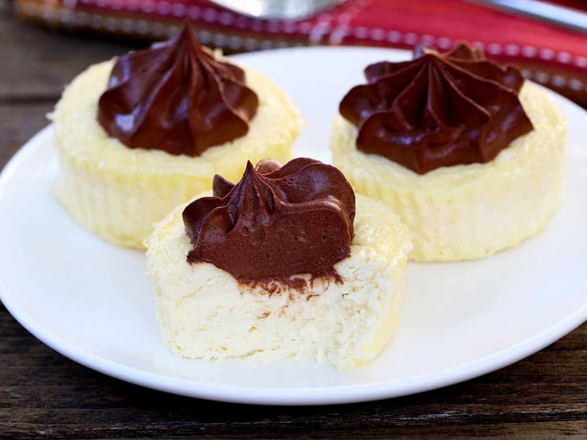 Three keto mini cheesecakes topped with chocolate whipped cream.