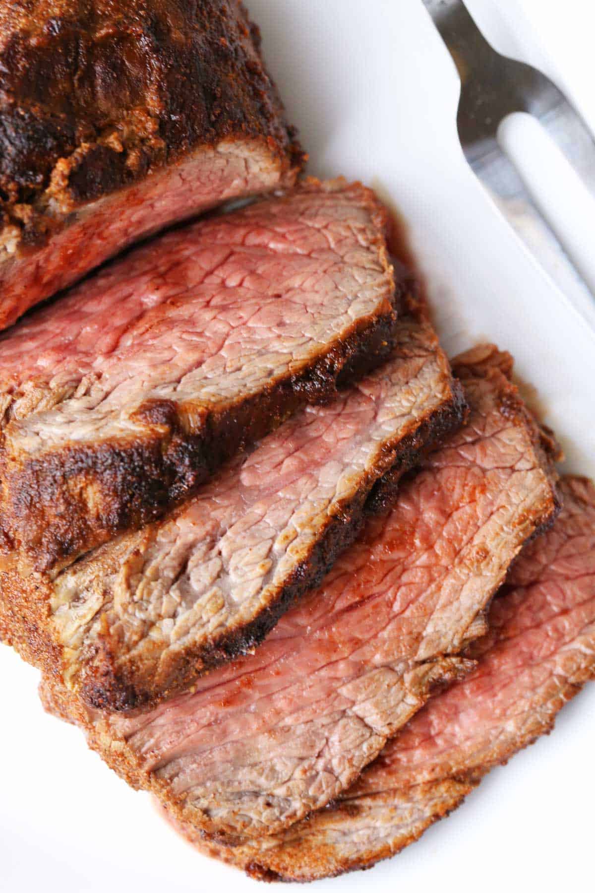 Tri-tip roast, sliced, served on a white plate. 