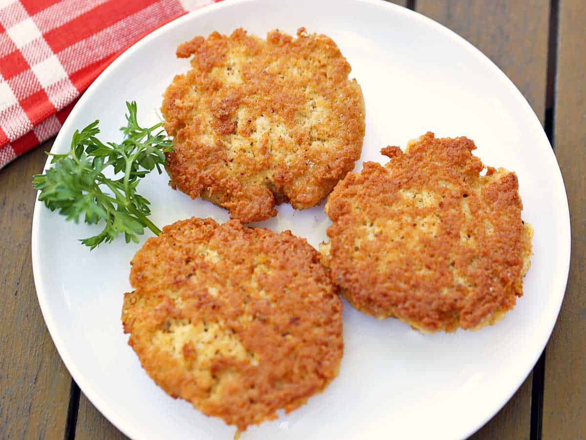 Three chicken patties served on a white plate. 