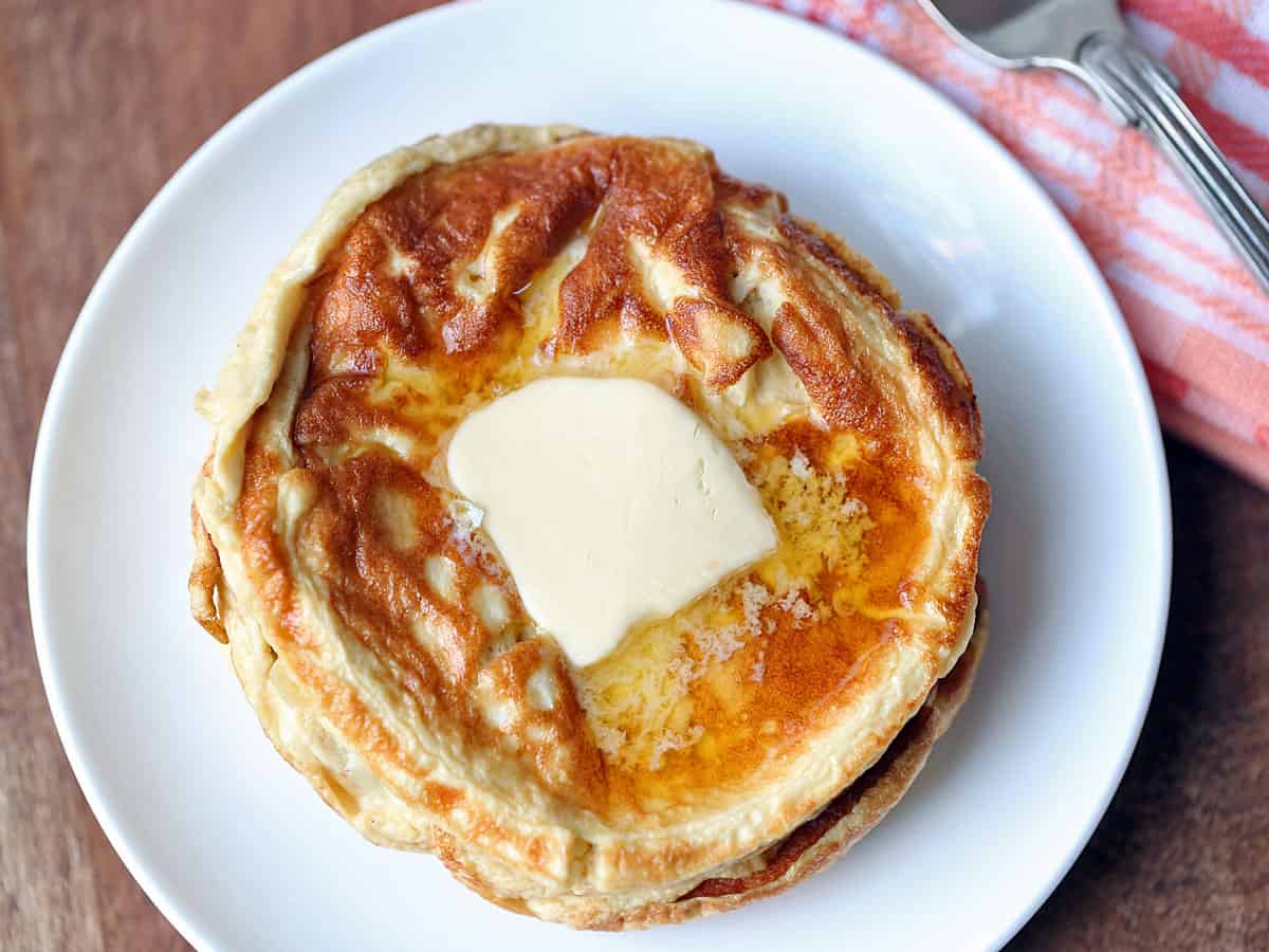 Keto cream cheese pancakes topped with butter, served on a white plate.