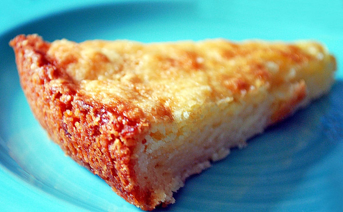 A slice of boterkoek - a Dutch butter cake, served on a blue plate. 