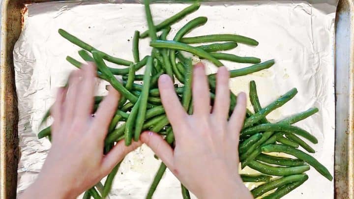 Tossing green beans with olive oil and spices.