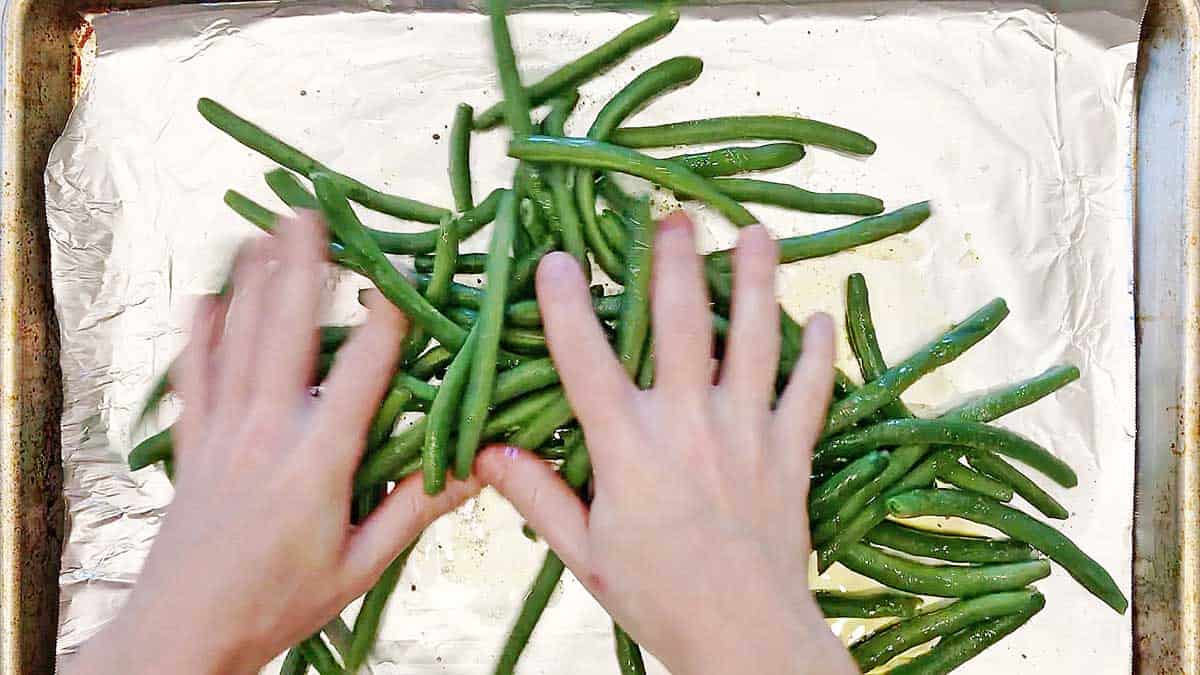 Step 2 for baking green beans: use your hands to coat them. 
