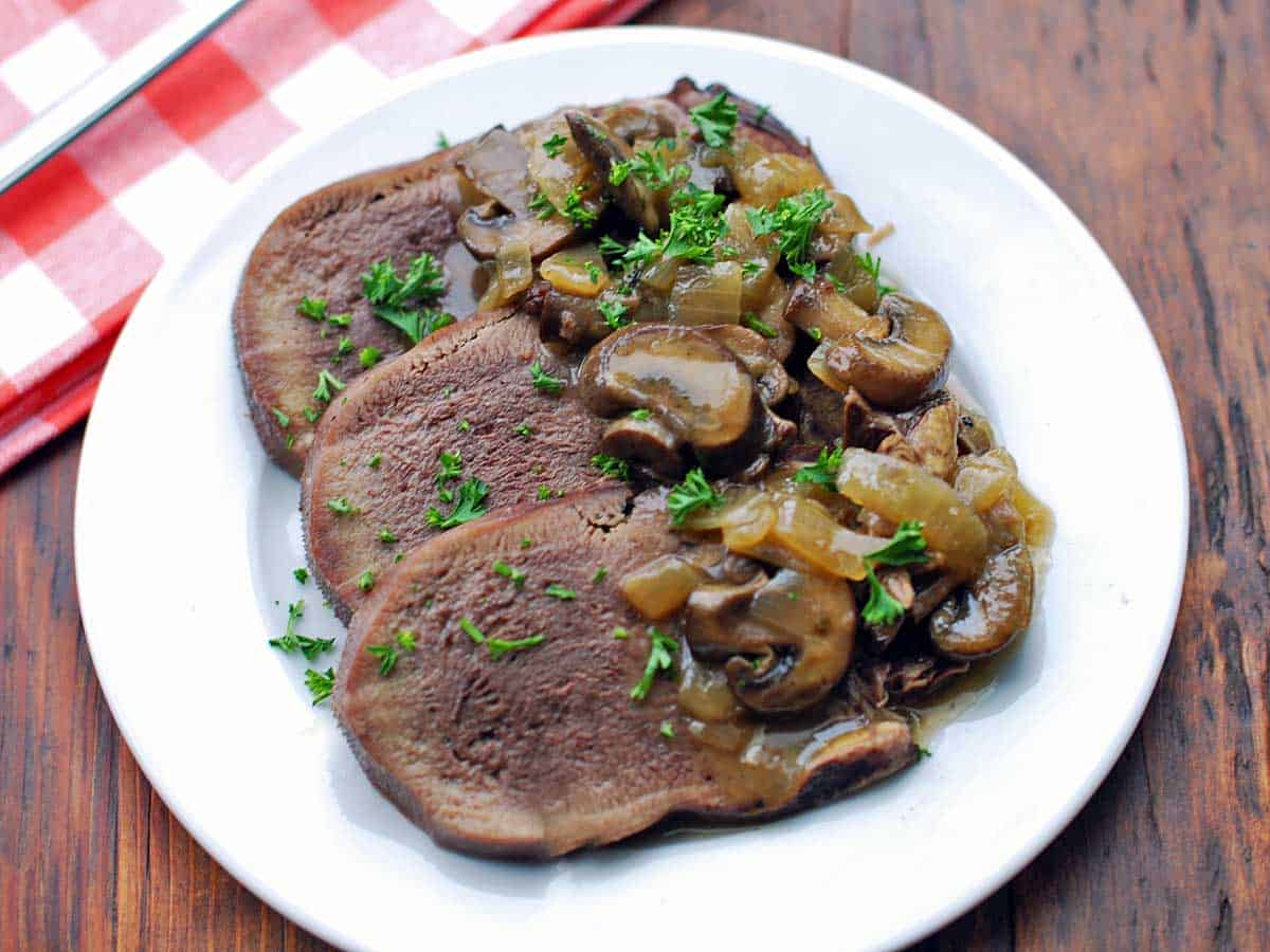 Slices of slow-cooked cow tongue, topped with mushrooms and onions. 