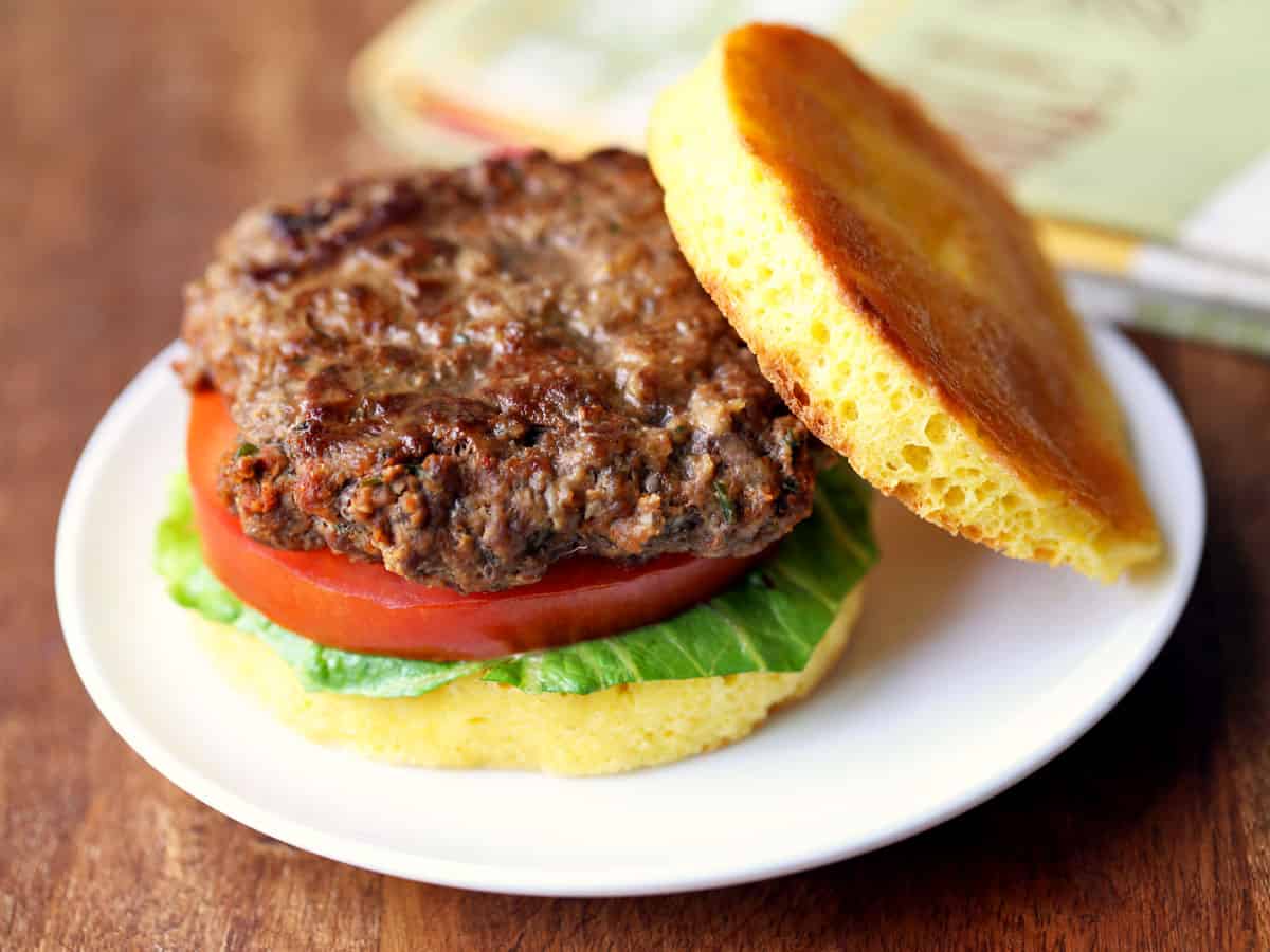 A bison burger served on a bun with lettuce and tomato. 