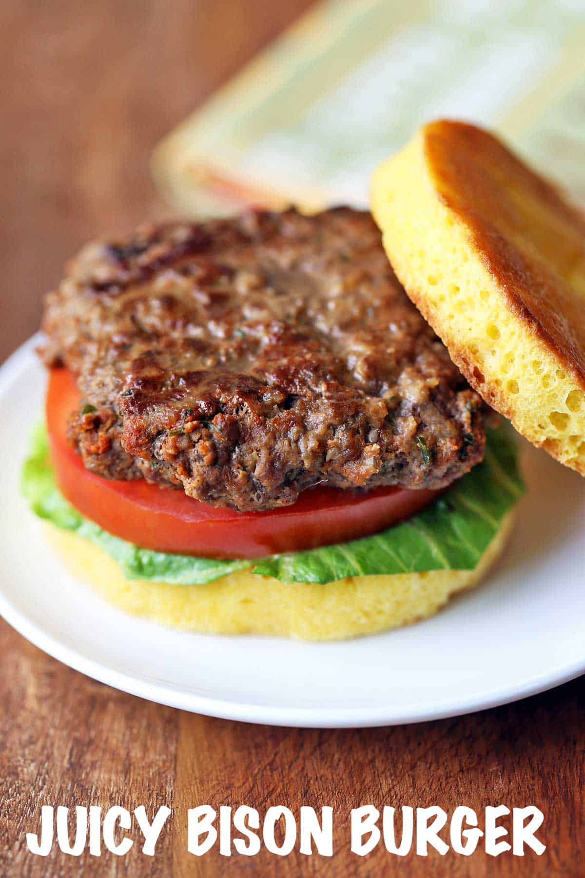Bison burger served on a bun with lettuce and tomato. 