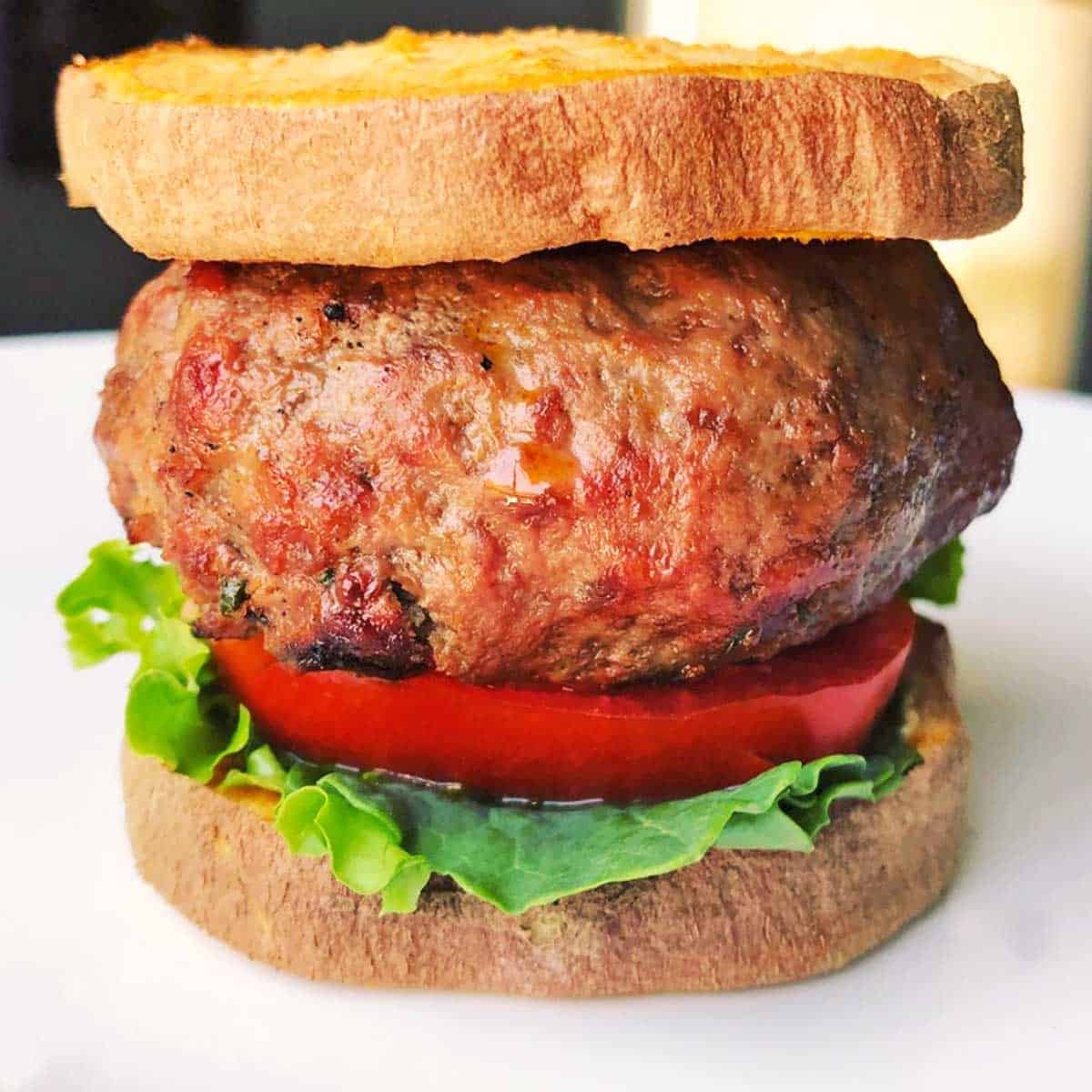 Closeup of a bison burger with a sweet potato bun.