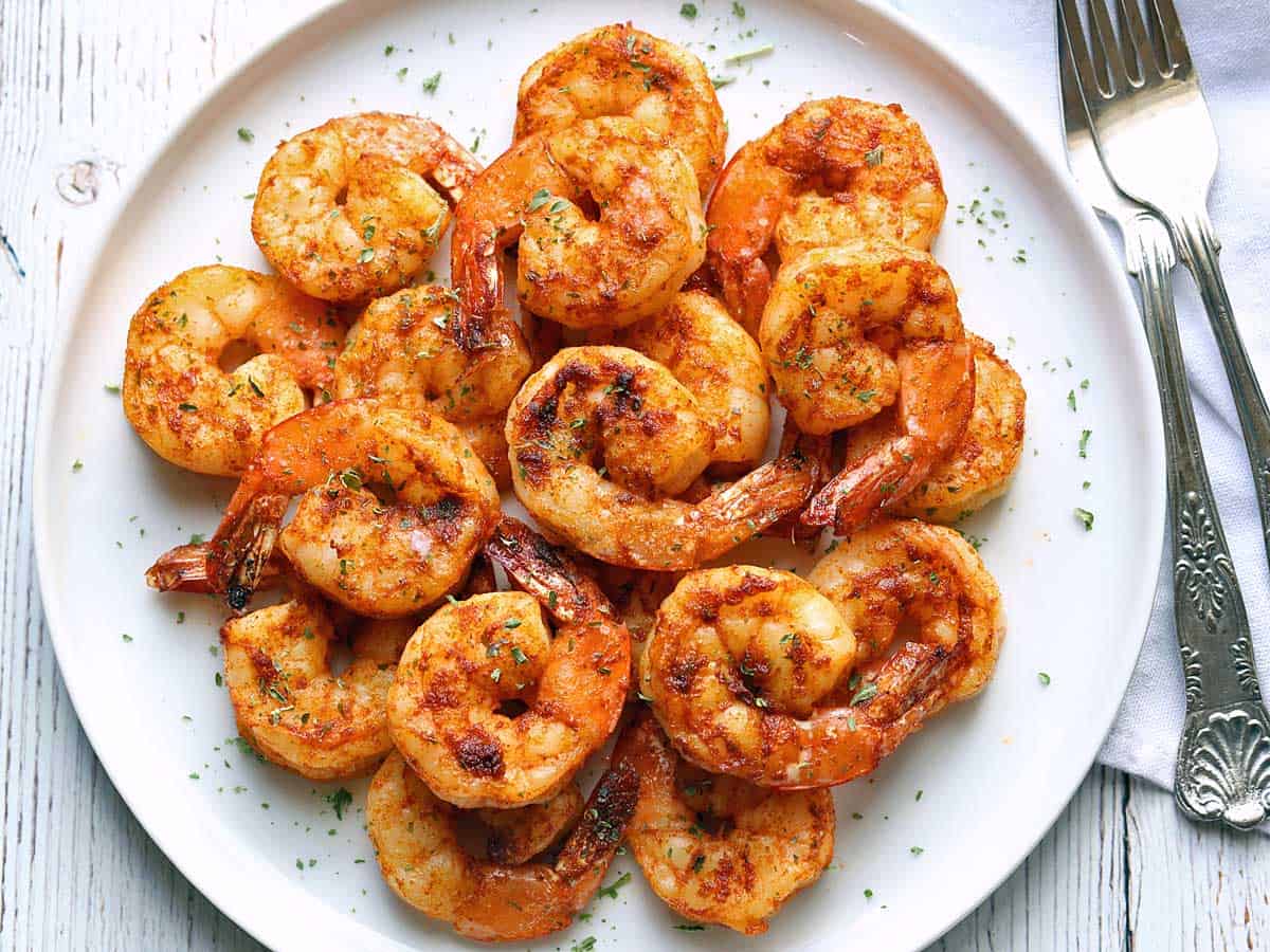 Broiled shrimp with cajun seasoning, served on a white plate.