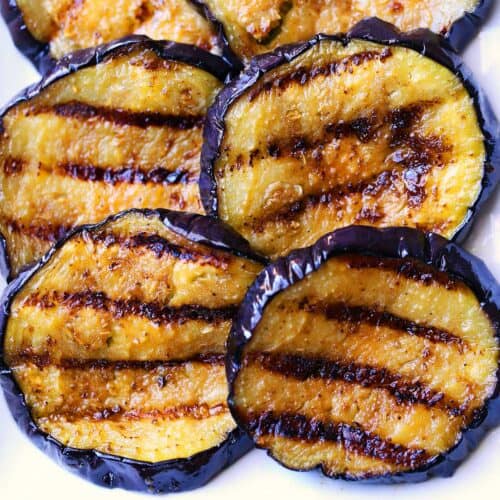 Grilled eggplant slices served on a white plate.