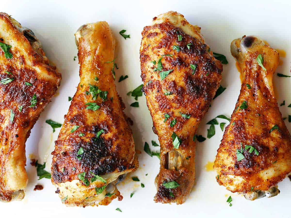 Baked chicken drumsticks served on a white plate.