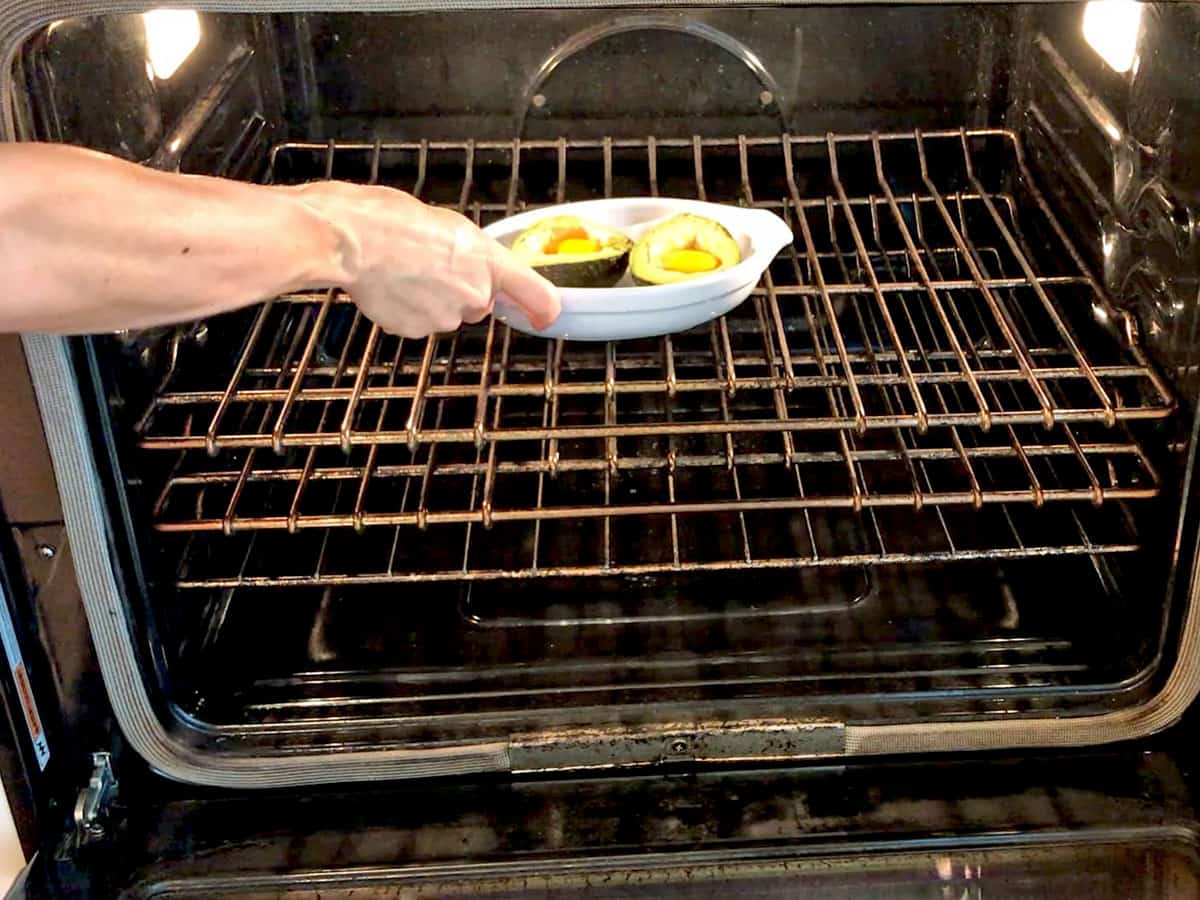 Placing the egg-stuffed avocado in the oven. 