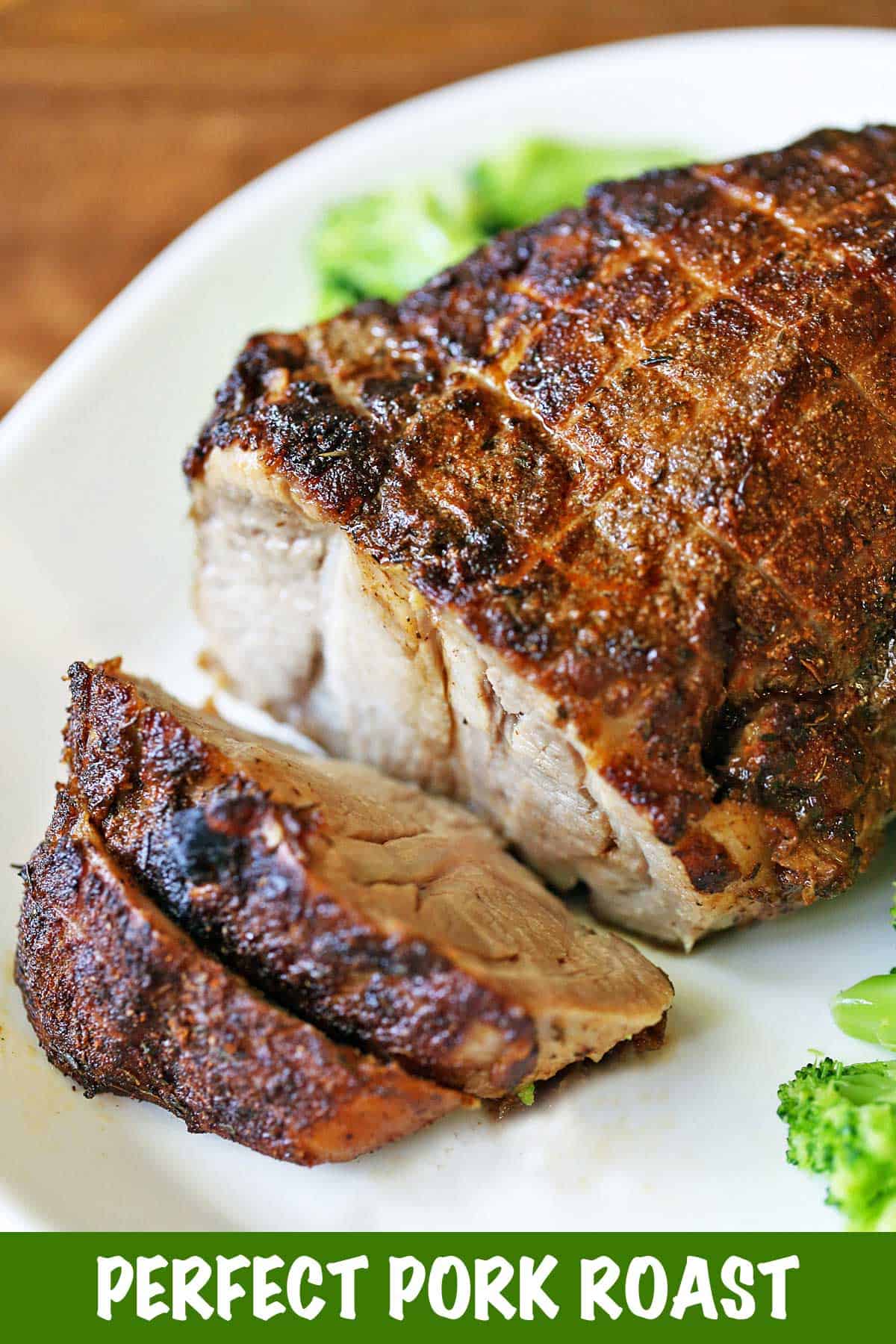 Oven-baked boneless pork roast served on a white platter with veggies. 