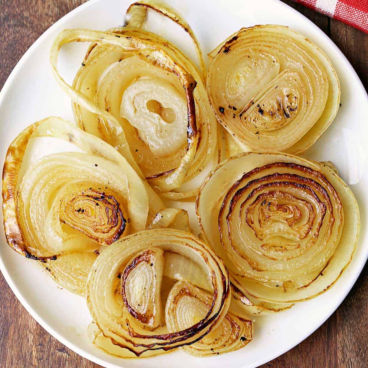 Roasted onions are served on a white plate.