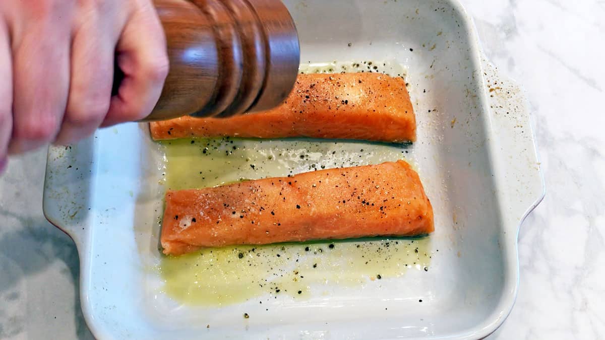 Seasoning salmon fillets before baking them. 