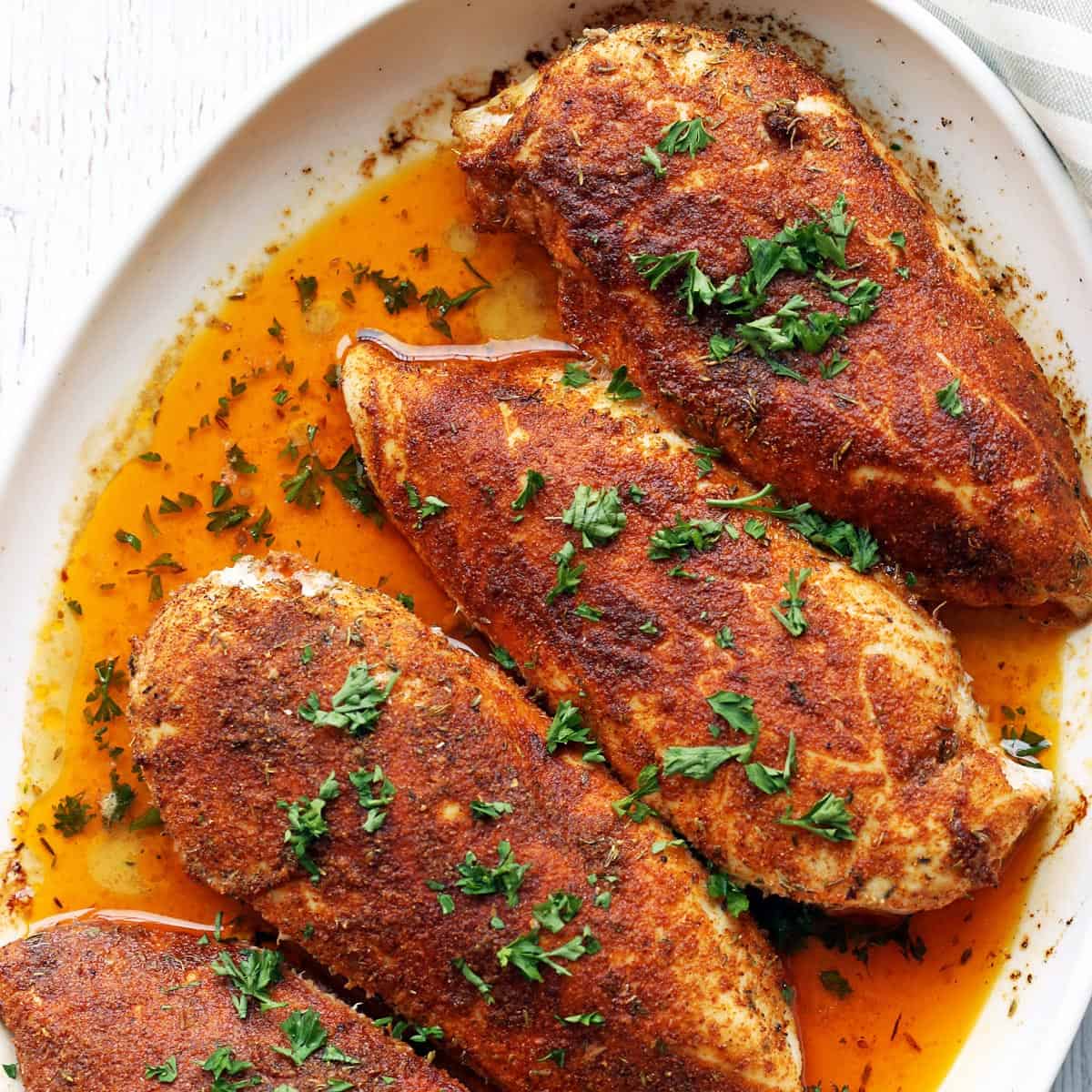Cajun chicken is served in a white baking dish.