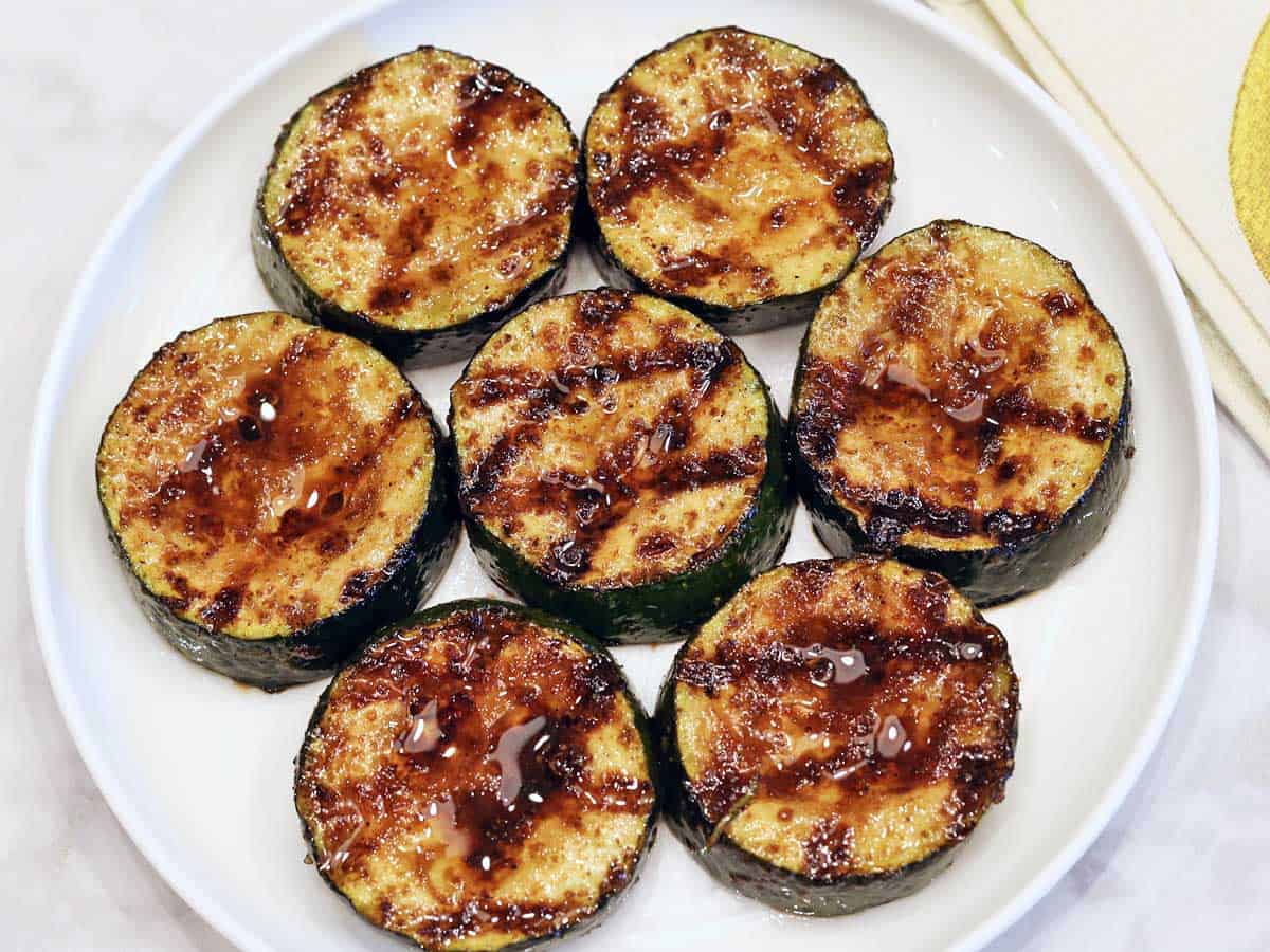 Grilled zucchini rounds served on a white plate. 