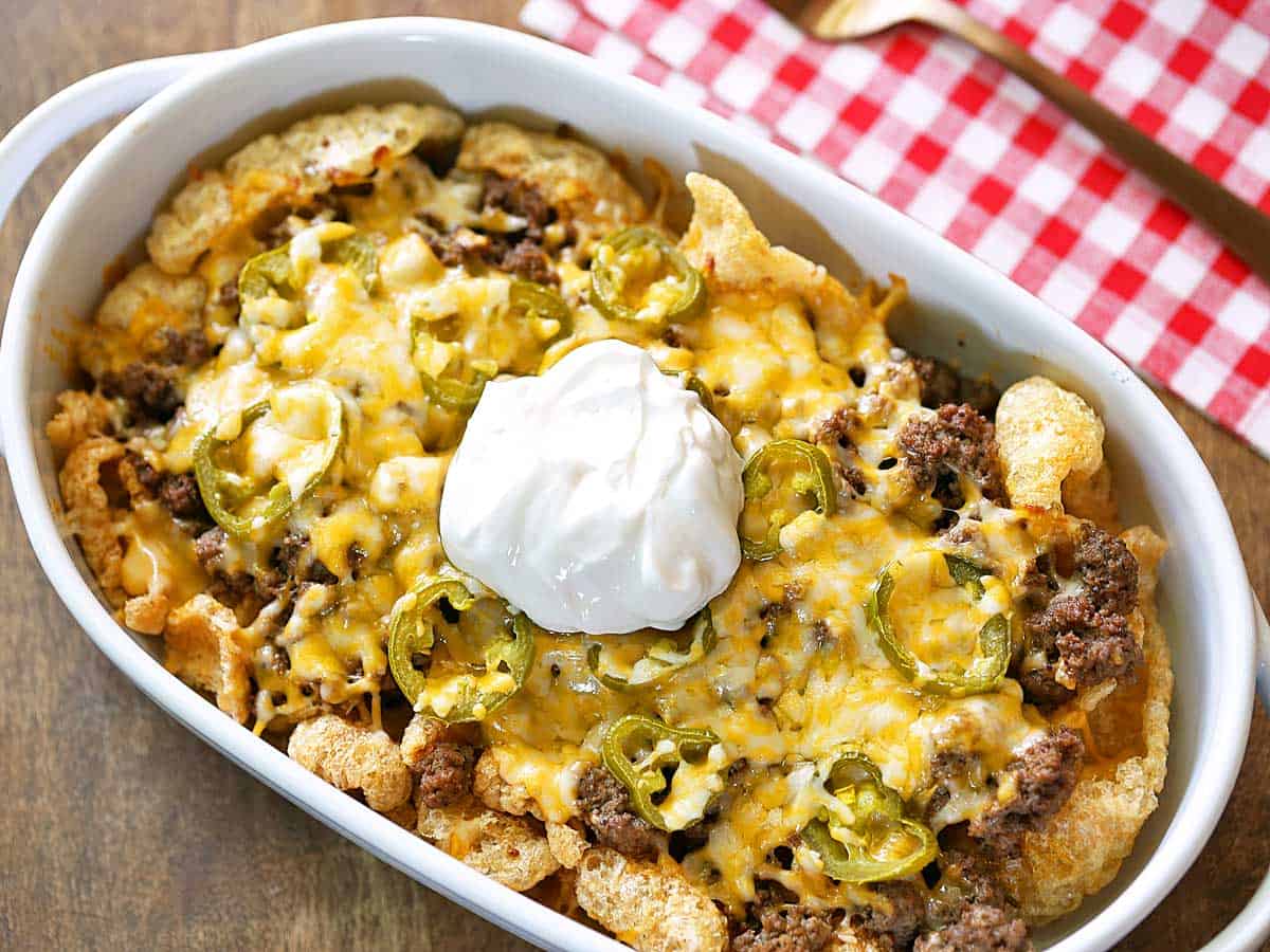 Keto nachos with sour cream served in a white baking dish. 