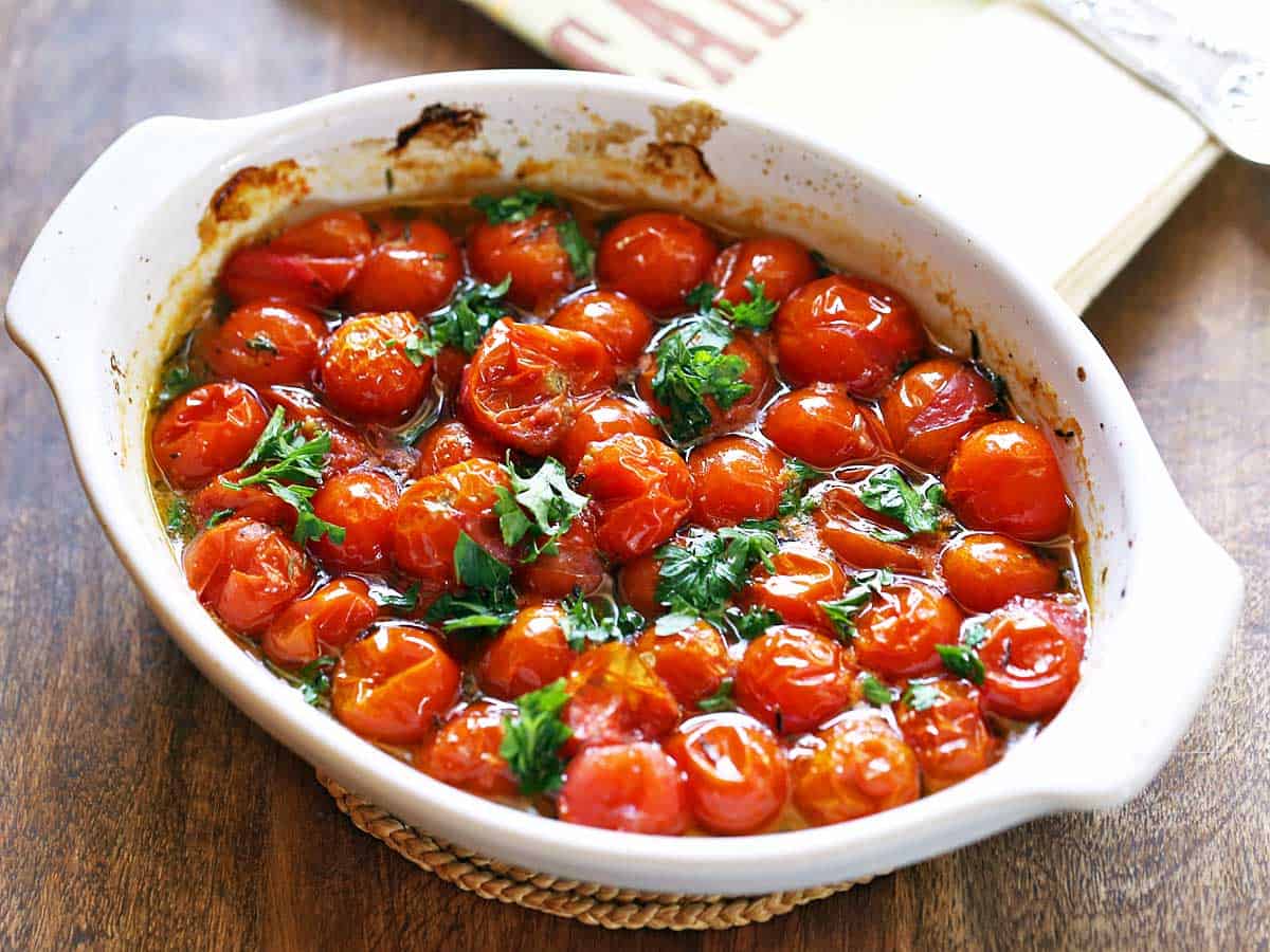 Roasted cherry tomatoes served in a white baking dish. 