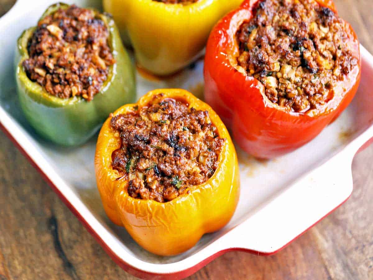 Four stuffed peppers without rice served in a square baking dish.