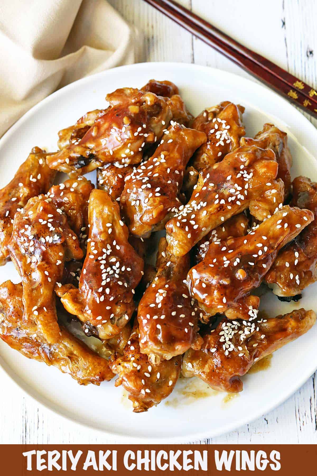Teriyaki wings topped with sesame seeds, served with chopsticks. 