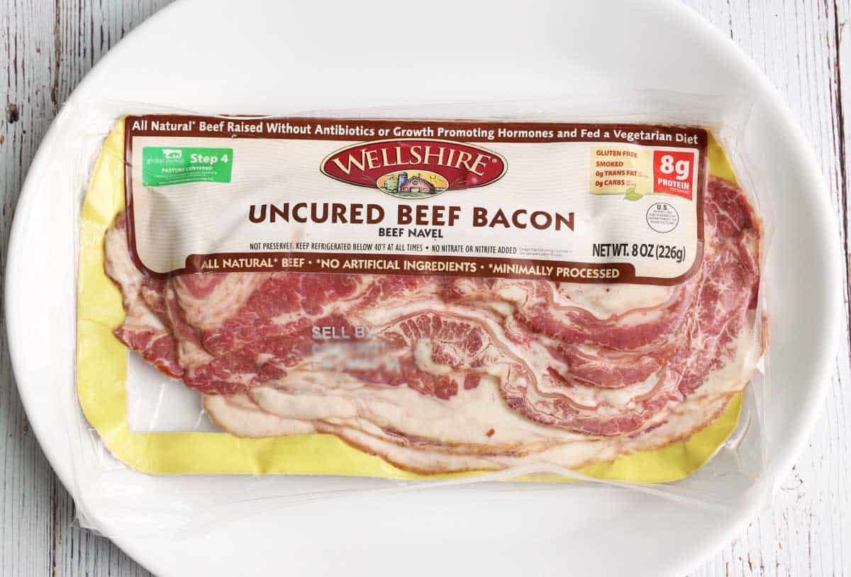 A package of beef bacon placed on a white serving plate. 